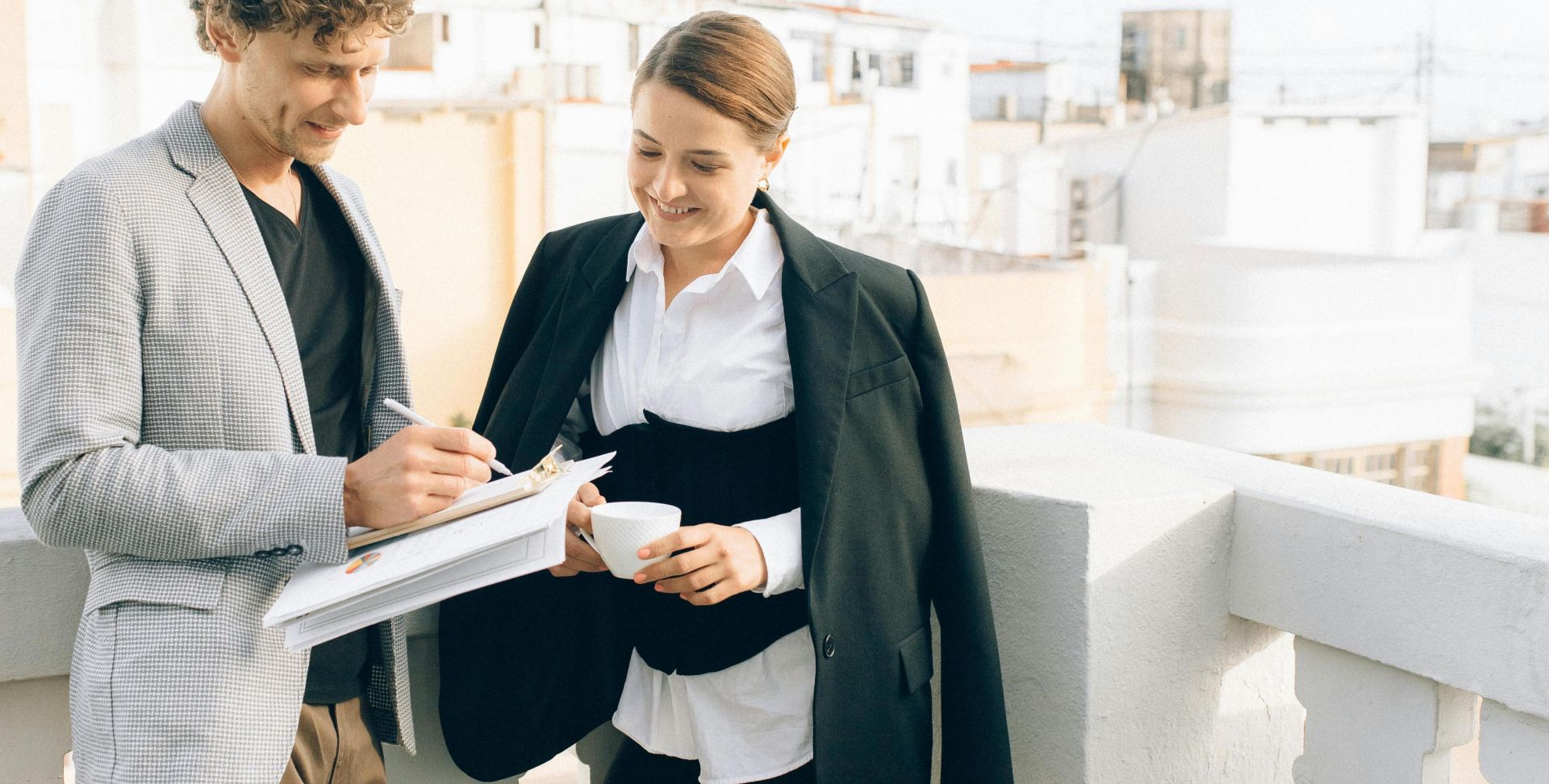 Two business professionals conversing on a rooftop, discussing strategies while enjoying a coffee break.