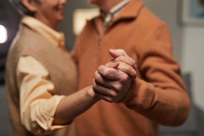 A senior couple warmly holding hands indoors, celebrating love and togetherness.