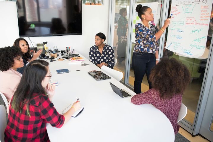 A multicultural office team engages in a collaborative brainstorming session around a conference table.