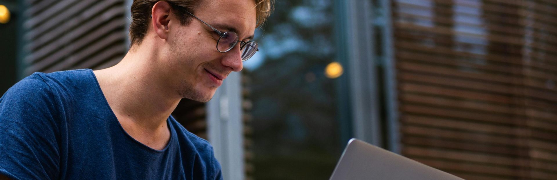 A young man sitting outdoors in Leiden, Netherlands, working on a laptop.