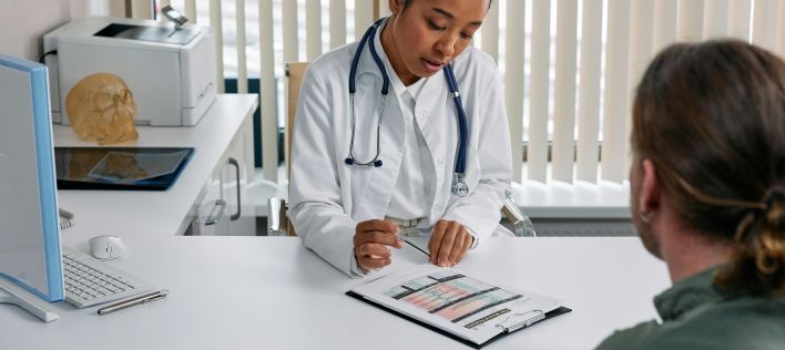 A doctor consulting with a patient in an office, discussing a medical chart.